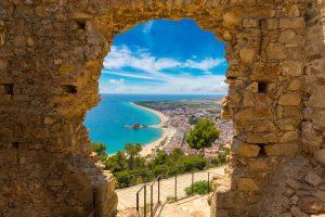 Blanes beach through a stone door of St. John Castle. Aerial panoramic view in Costa Brava in a beautiful summer day, Spain